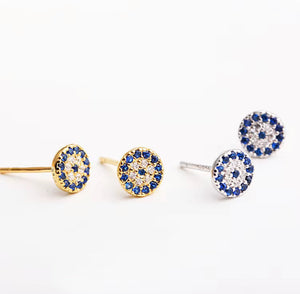Sterling silver and gold-plated sterling silver evil eye stud earrings with blue and white cubic zirconia stones, protective talisman jewellery symbolizing luck and protection, displayed on a white background.