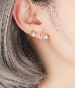 Woman wearing mismatched sun and moon stud earrings